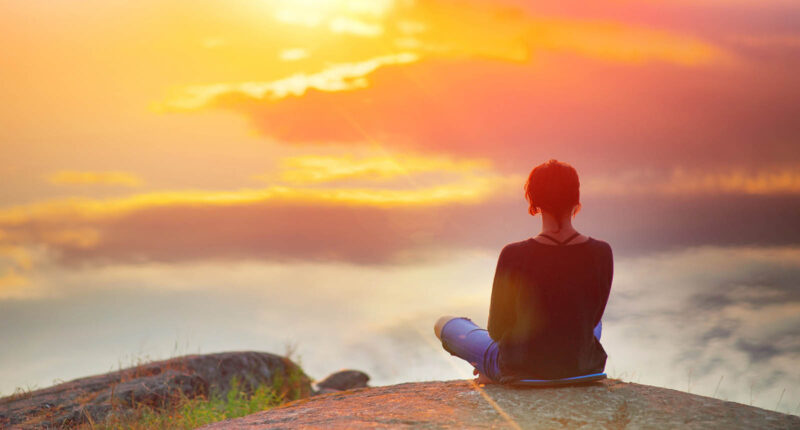 woman looking at sun in horizon