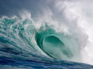 a large wave curls over with water spraying