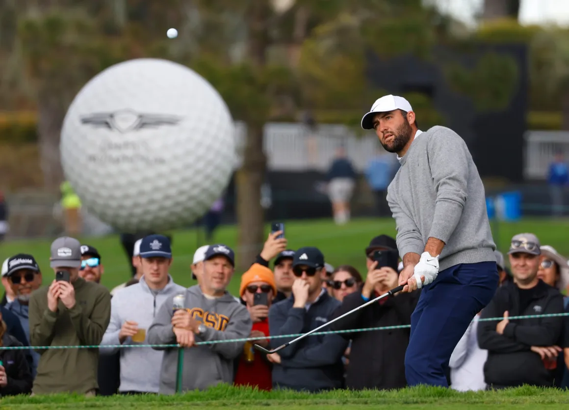 a golfer swings with the ball in the air in front of a crowd
