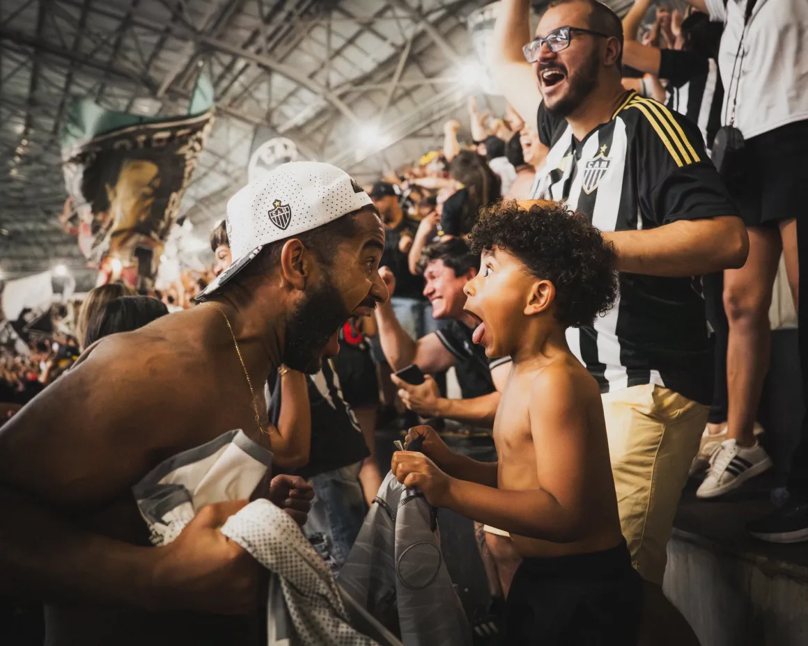 a man leans down to scream with a young boy in a crowded stadium