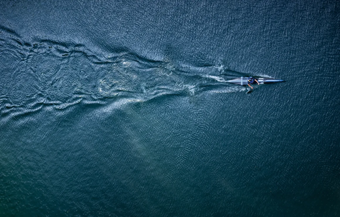 a slim boat cuts through rippled water