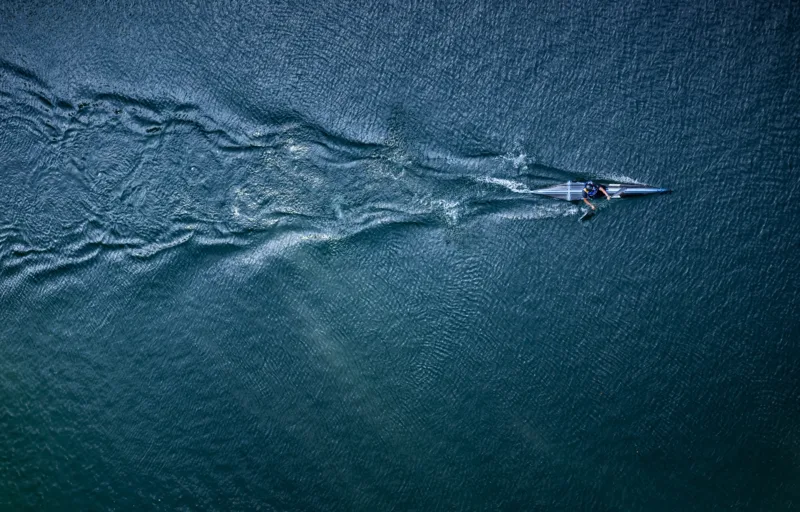 a slim boat cuts through rippled water