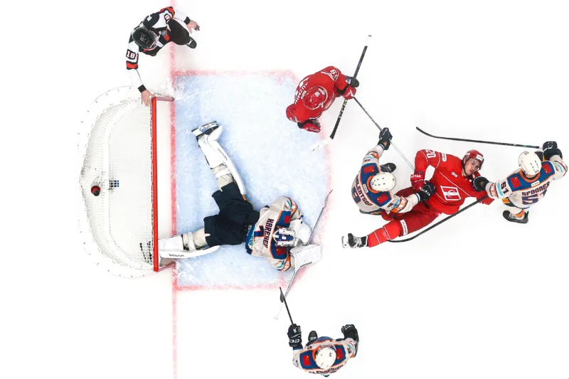 hockey players sprawl on the ice in front of the net