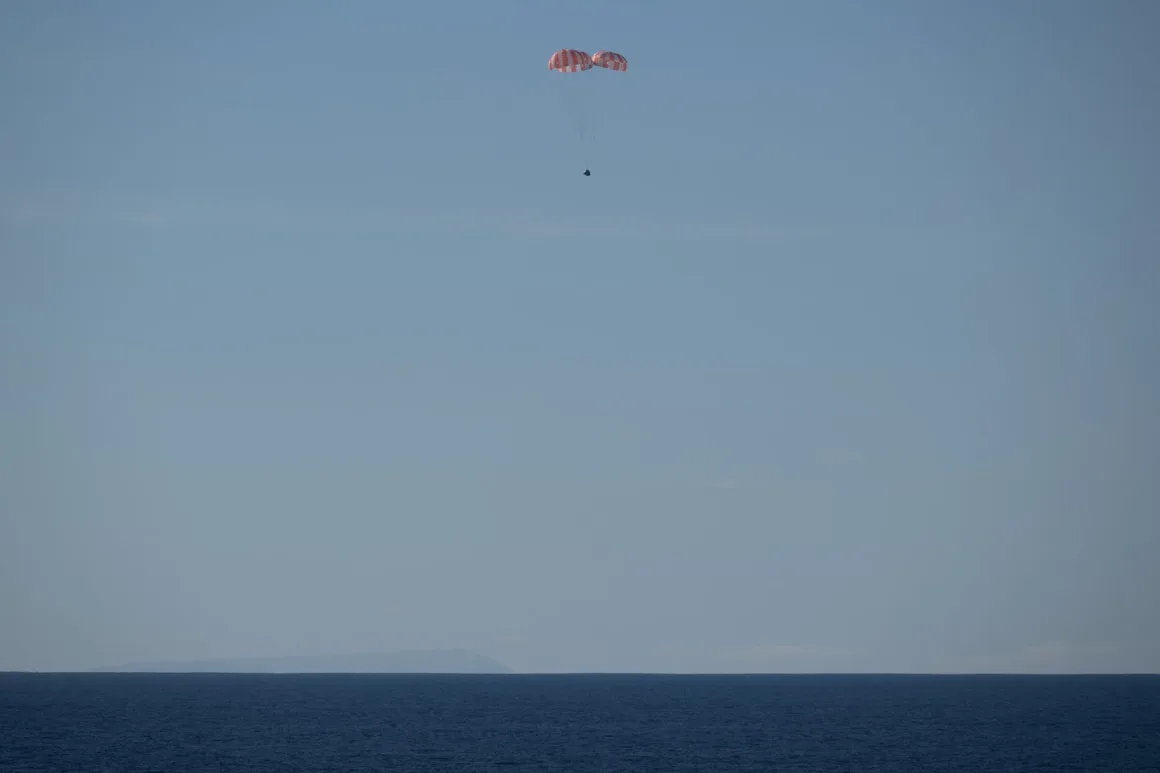 Kırmızı-beyaz paraşütlü küçük bir kapsül, sakin mavi okyanusa doğru alçalıyor; ufukta kara silueti.