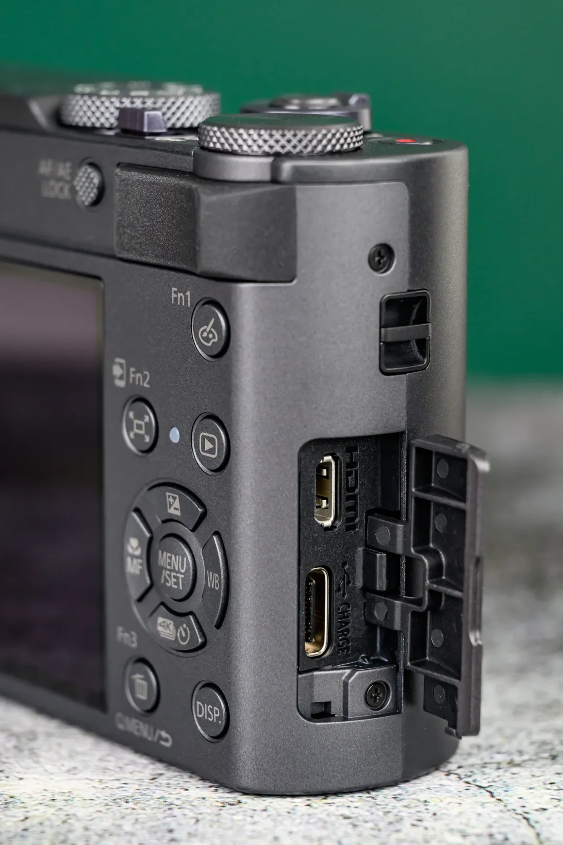 Panasonic Lumix ZS300 İnceleme: Eski Model Daha İyiydi? 8 Bir dijital kameranın yan tarafının yakın planı; port kapağı açık ve HDMI ile USB-C girişleri görünüyor. Kamera gövdesinde çeşitli kontrol düğmeleri de yer alıyor.
