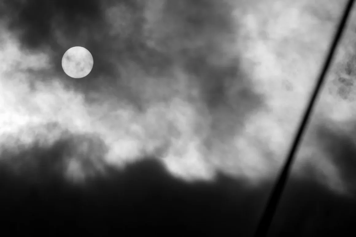 Panasonic Lumix ZS300 İnceleme: Eski Model Daha İyiydi? 14 Parlak yuvarlak bir ay, dramatik koyu bulutlar tarafından kısmen örtülmüş. Gri tonlu gökyüzünde sağ tarafta bulanık çapraz bir çizgi yer alıyor.