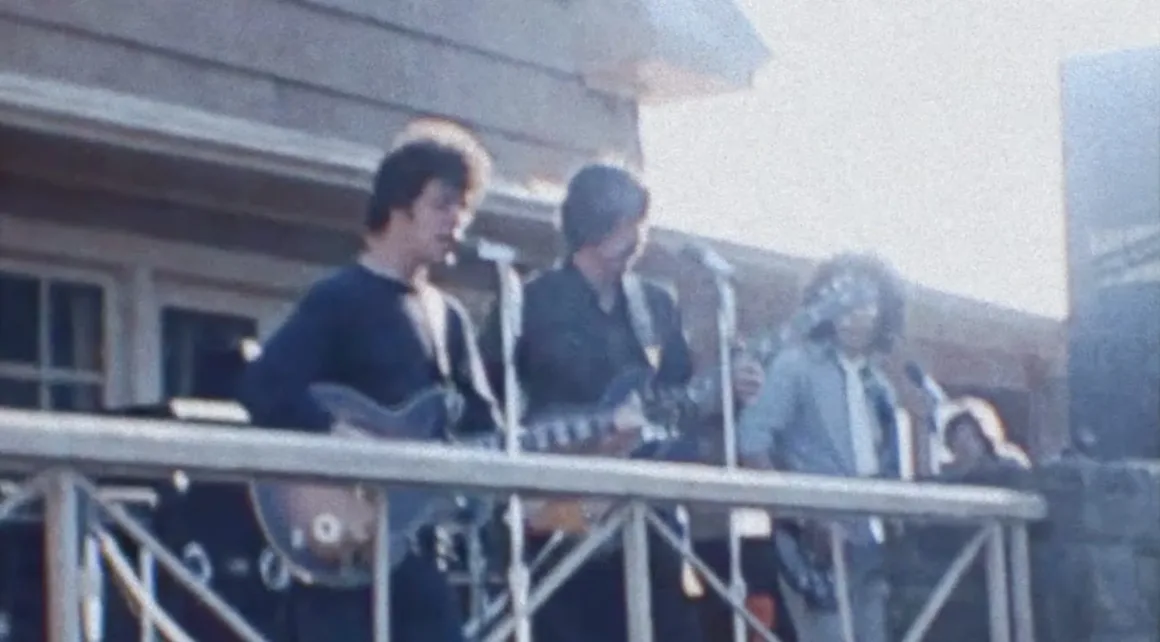 The Velvet Underground’ın Vietnam Protestosundaki Kayıp Görüntüleri
1969 yılında açık havada sahnede elektrik gitar çalan üç müzisyen, mikrofonların önünde performans sergiliyor, arka planda bina ve korkuluklar görünüyor.