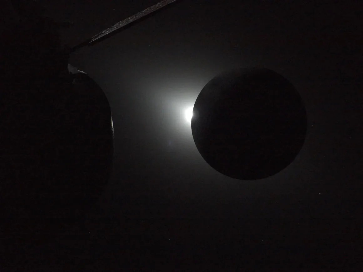 Uzayda parlak bir ışık kaynağı önünde silüet halinde görünen karanlık dairesel bir cisim; yüksek kontrastlı dramatik bir görünüm.