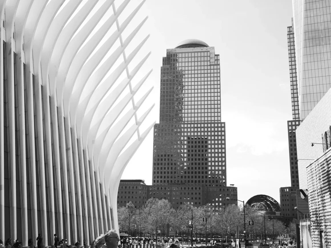 Kareden Önce: Bir Yönetmenin Sokak Fotoğrafçılığı Yaklaşımı 12 New York City’de World Trade Center’daki Oculus yapısının siyah beyaz fotoğrafı. Arka planda yüksek binalar ve ağaçlar, ön planda ise yürüyen insanlar görülüyor.