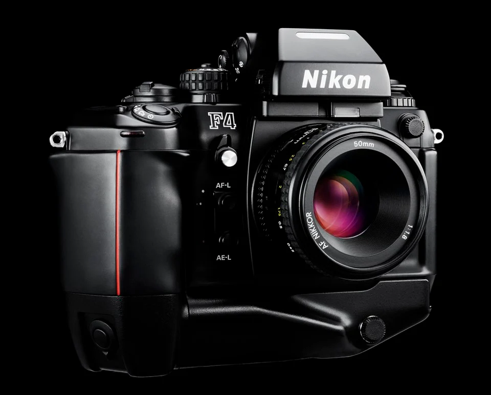 Siyah arka plan önünde 50mm lens takılı Nikon F4 film kamerasının yakın plan görüntüsü; kameranın düğmeleri, kadranları ve marka detayları net şekilde görülüyor.