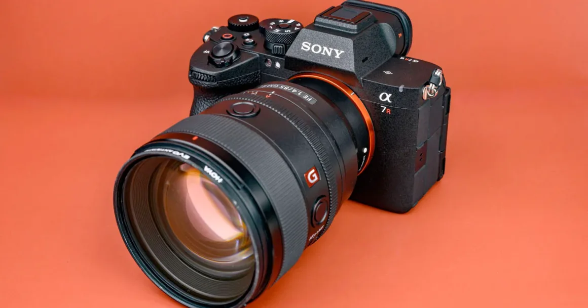 Sony a7R VI Tanıtıldı: 66.8MP Stacked Sensör ve 30 FPS
Turuncu bir yüzey üzerinde duran, büyük zoom lens takılmış Sony Alpha 7R aynasız kamera. Gövde üzerindeki kontrol tekerleri ve logolar görünür durumda.