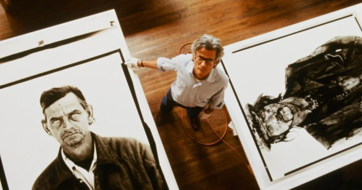 Ron Howard’ın Richard Avedon Belgeseli Cannes’da Prömiyer Yapacak
Gözlüklü bir adam, yerde duran iki büyük siyah-beyaz portre çalışmasının arasında durarak kameraya doğru bakıyor. Zemin ahşap ve yanında turuncu bir kablo görülüyor.