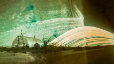 the rounded metal shield over chornobyl looms in the distance with streaks of light next to it