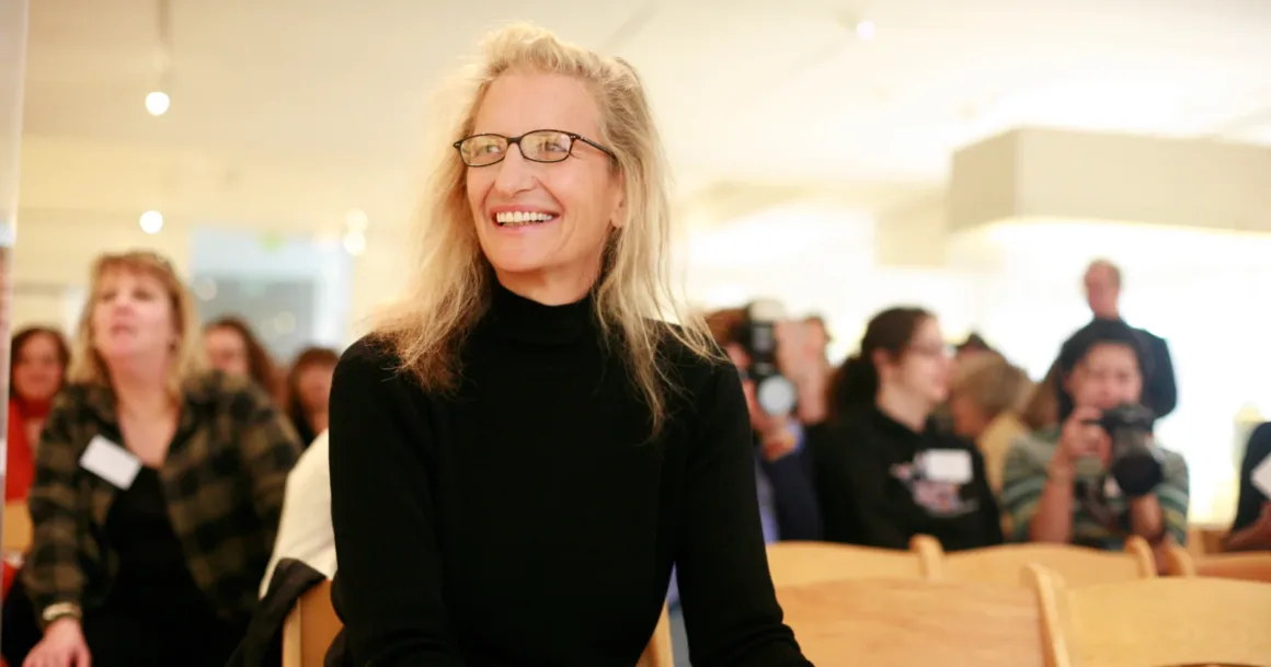 Annie Leibovitz, Justin ve Hailey Bieber Fotoğrafı İçin Telif Hakkı Davası Açtı 1 Annie Leibovitz, Justin ve Hailey Bieber Fotoğrafı İçin Telif Hakkı Davası AçtıUzun sarı saçlı, gözlüklü ve siyah balıkçı yaka kazak giymiş bir kadın, arka planda oturan insanların bulunduğu aydınlık bir odada gülümseyerek oturuyor.