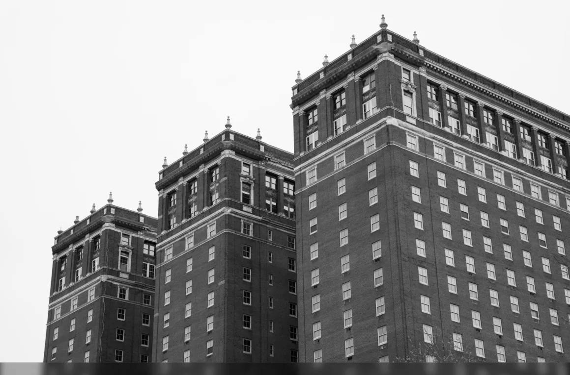 HiRezGo: Fotoğrafları Sıkıştırmadan Paylaşmanın Yeni Yolu 4 Black and white photo of three adjoining multi-story brick buildings with decorative rooflines and many windows, viewed from a low angle against a plain sky.