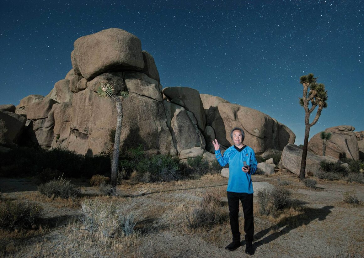 Dünyanın En Karanlık Gökyüzlerinin Güzelliğini Yansıtan 31 Ödüllü Fotoğraf 33 A man wearing a blue Star Trek-style uniform stands in a desert landscape at night, making a Vulcan salute gesture under a starry sky.