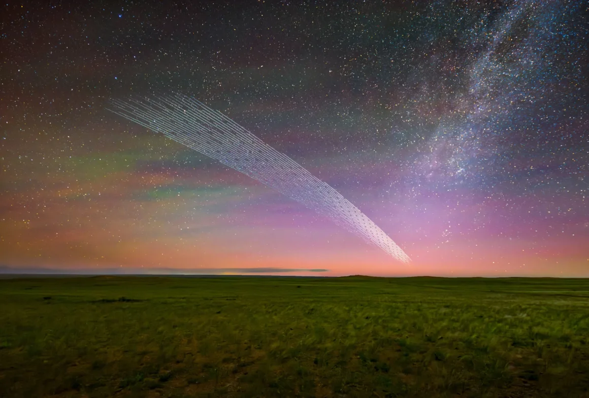Dünyanın En Karanlık Gökyüzlerinin Güzelliğini Yansıtan 31 Ödüllü Fotoğraf 13 A long-exposure shot shows a train of satellite streaks arching across a night sky above a grassy landscape and the Milky Way.
