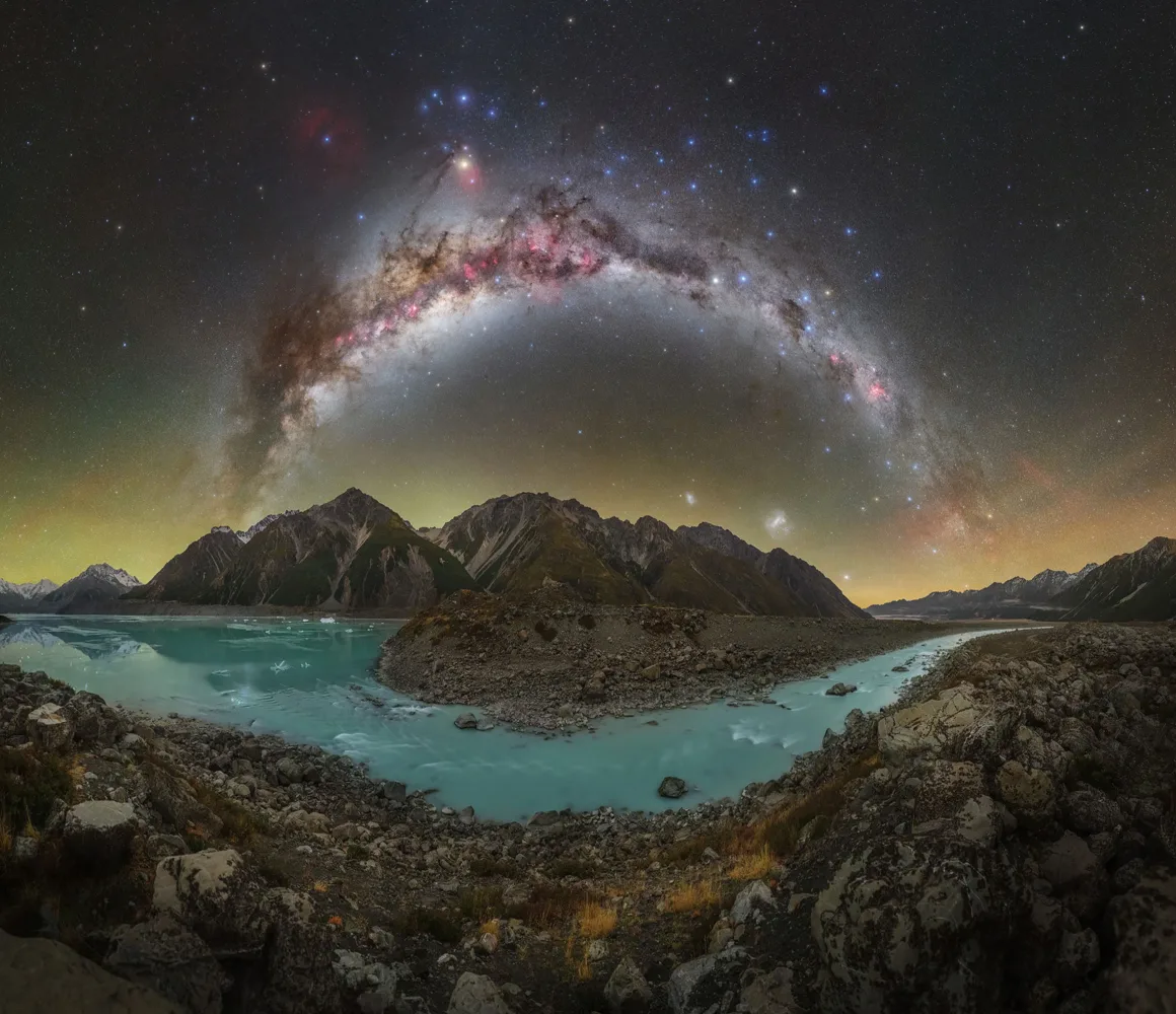 Dünyanın En Karanlık Gökyüzlerinin Güzelliğini Yansıtan 31 Ödüllü Fotoğraf 8 A panoramic view of a turquoise glacial lake and rocky shoreline beneath a vibrant, arched Milky Way galaxy over mountains.