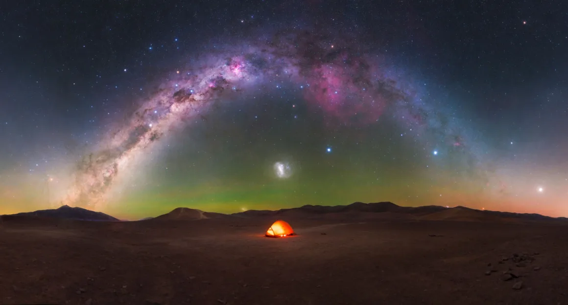 Dünyanın En Karanlık Gökyüzlerinin Güzelliğini Yansıtan 31 Ödüllü Fotoğraf 26 A glowing orange tent sits in a vast, dark desert landscape beneath a panoramic arch of the Milky Way galaxy.