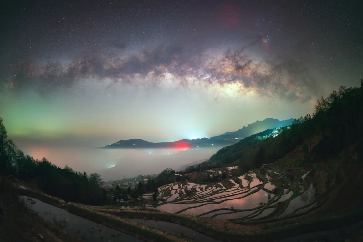 Dünyanın En Karanlık Gökyüzlerinin Güzelliğini Yansıtan 31 Ödüllü Fotoğraf 15 A panoramic view of the Milky Way galaxy arching over terraced rice fields filled with water, with fog settling in the valley.