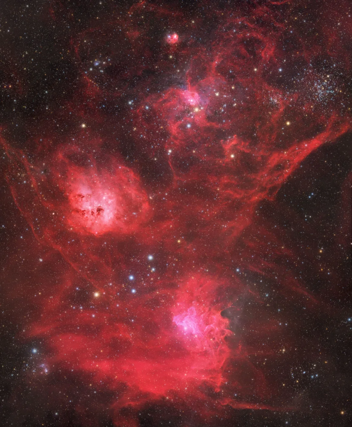 Dünyanın En Karanlık Gökyüzlerinin Güzelliğini Yansıtan 31 Ödüllü Fotoğraf 21 A vast, vibrant red emission nebula fills the frame, featuring glowing gas clouds, dark dust lanes, and scattered star clusters.