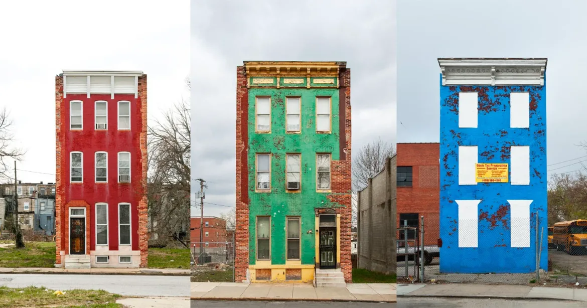 Three narrow, multi-story row houses painted bright red, green, and blue stand side-by-side, with the blue house featuring boarded-up windows and a tax preparation sign.