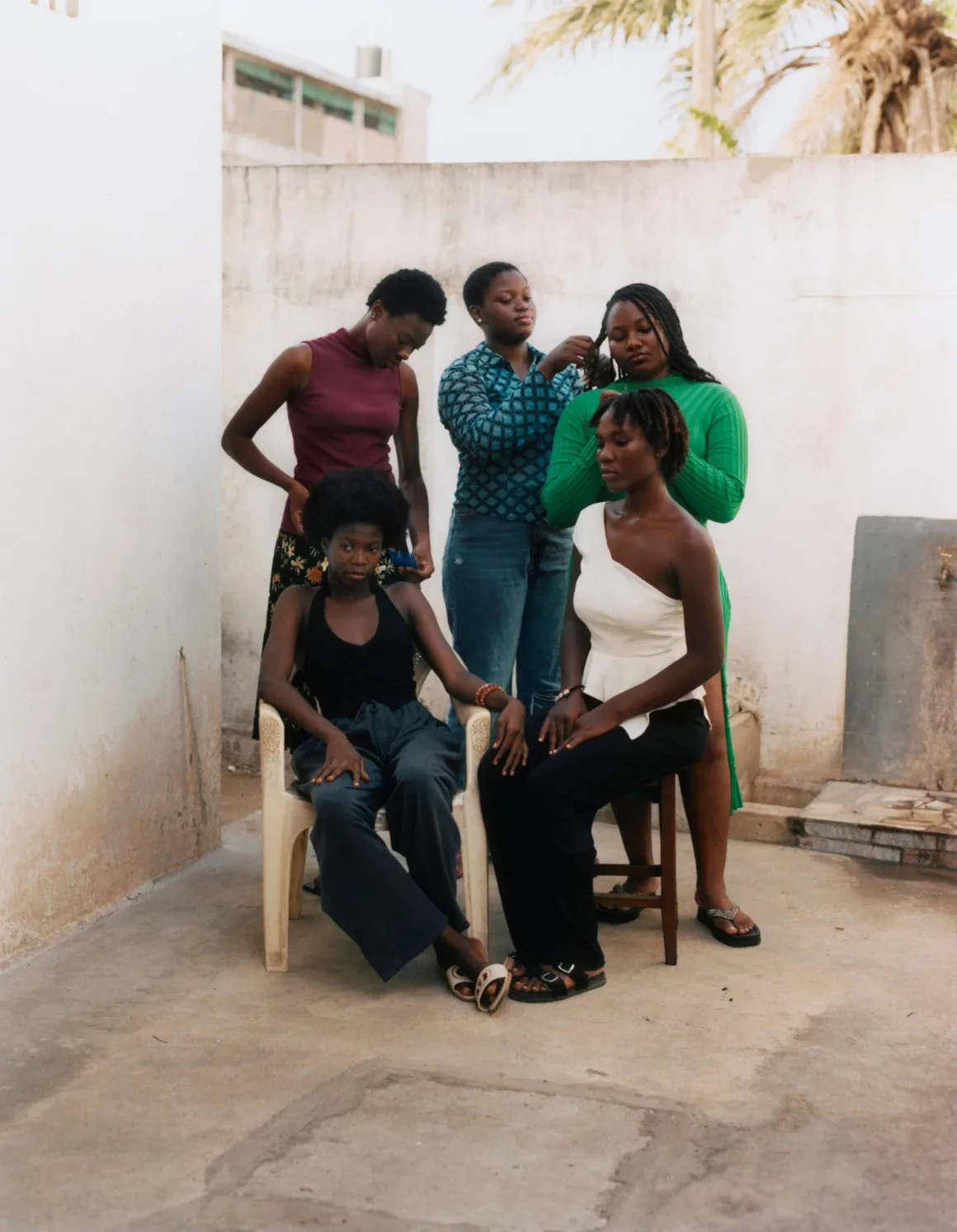 Winston Taylor Photo Portrait Prize 2026 10 Four young Black women gather outdoors, with two seated in chairs while the others stand behind them styling their hair.