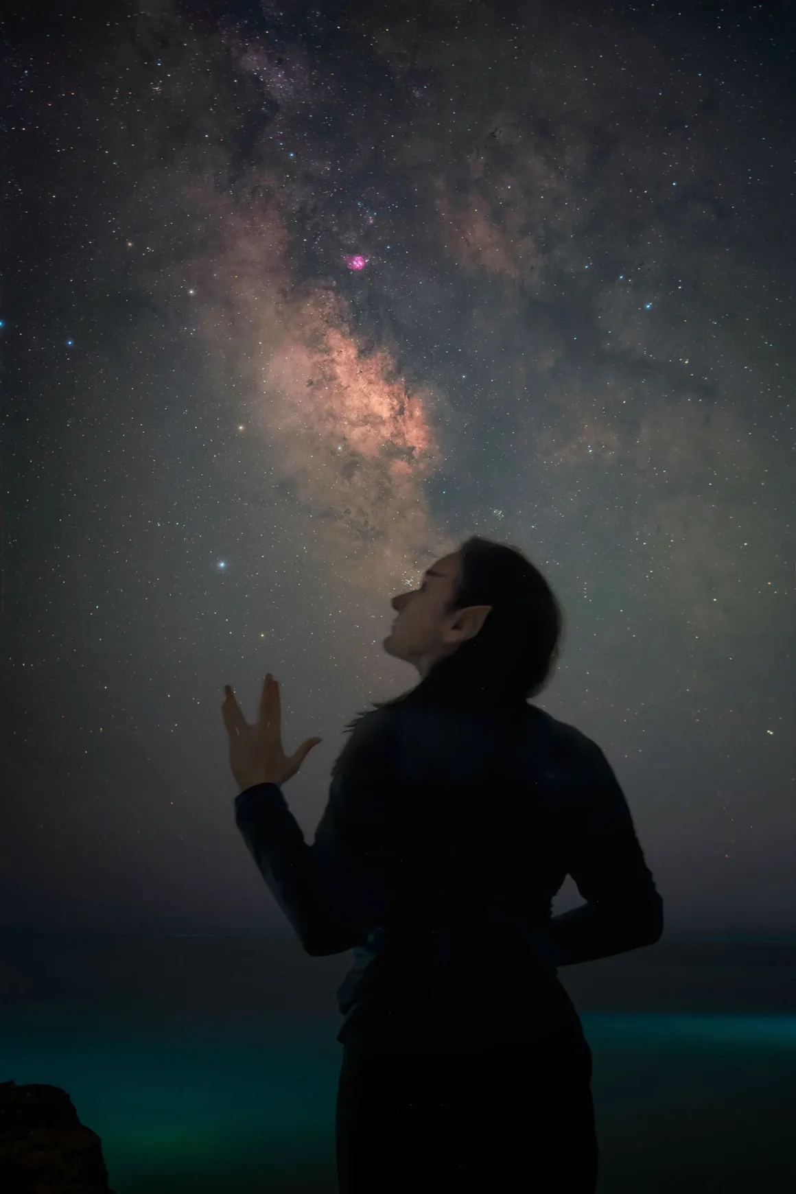Dünyanın En Karanlık Gökyüzlerinin Güzelliğini Yansıtan 31 Ödüllü Fotoğraf 32 A silhouette of a person with pointed ears stands against a starry night sky, reaching a hand toward the Milky Way.