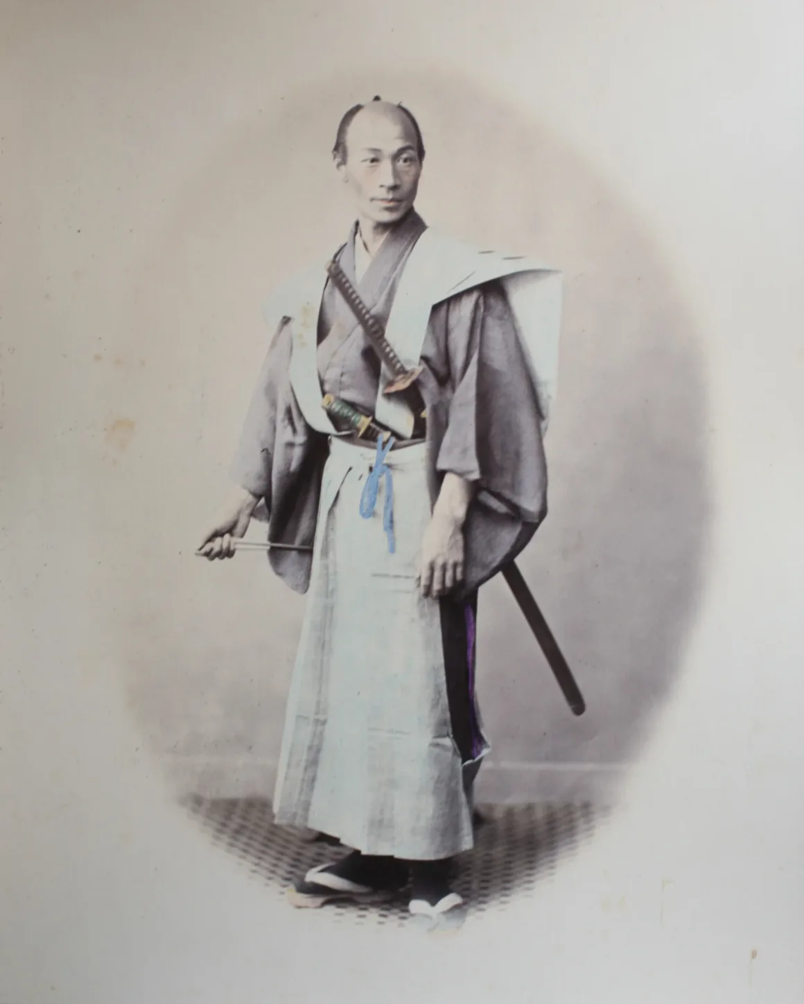 Fotoğrafçı, Japonya’nın Unutulmuş 19. Yüzyıl Fotoğraflarını Buldu ve Bugün Yeniden Yorumladı 19 Geleneksel tören kıyafetleri içindeki Japon görevli, kuşağına yerleştirilmiş iki kılıçla stüdyoda poz veriyor.