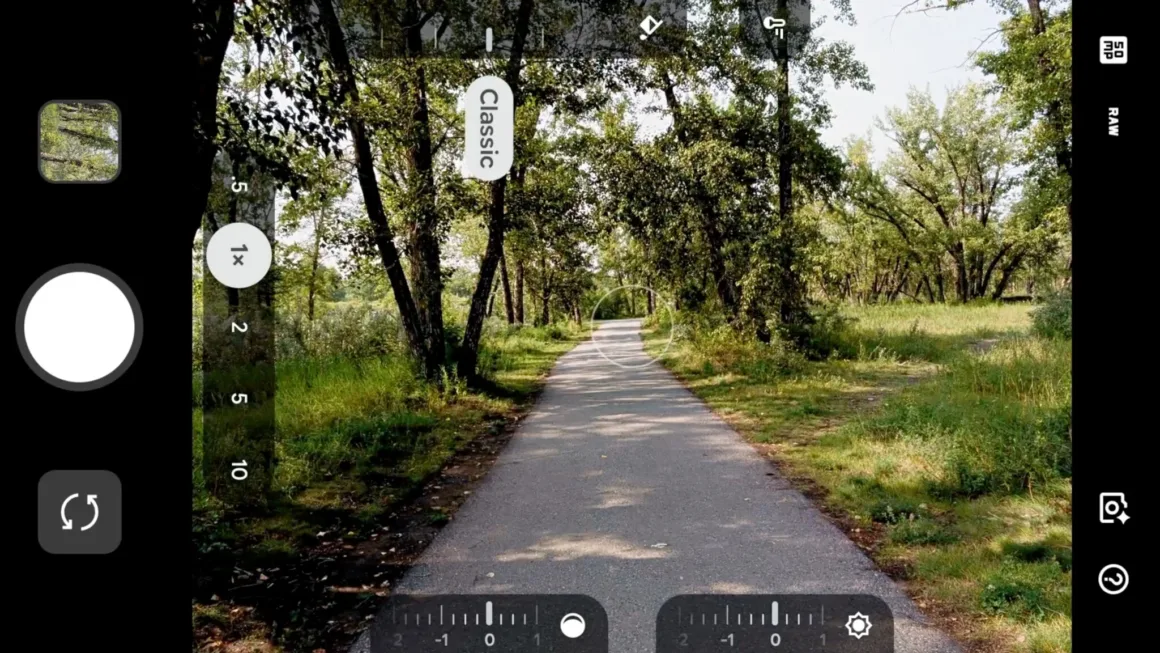 Google Pixel 11 Pro XL İncelemesi: Küçük Ama Anlamlı Bir Adım 43 Bir akıllı telefonun kamera arayüzünde, ağaçlık bir alandan geçen asfalt yol görülüyor; ekranda yakınlaştırma kontrolleri, pozlama ayarları ve deklanşör düğmesi yer alıyor.