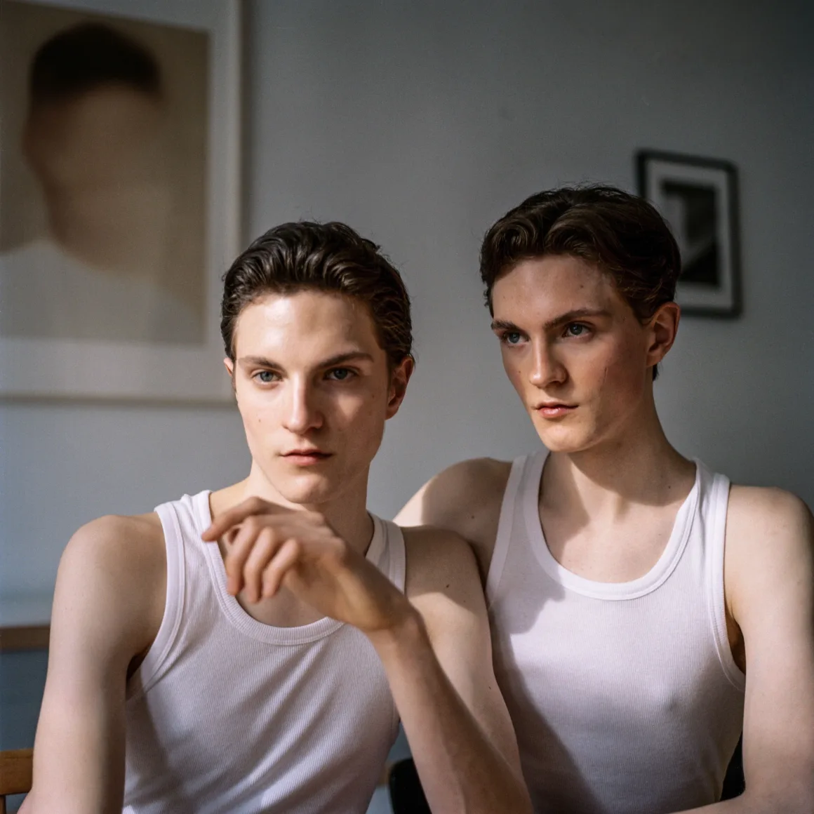 Winston Taylor Photo Portrait Prize 2026 12 Two young men with similar features and dark hair wear white tank tops, sitting side-by-side in a room with framed art on the wall.