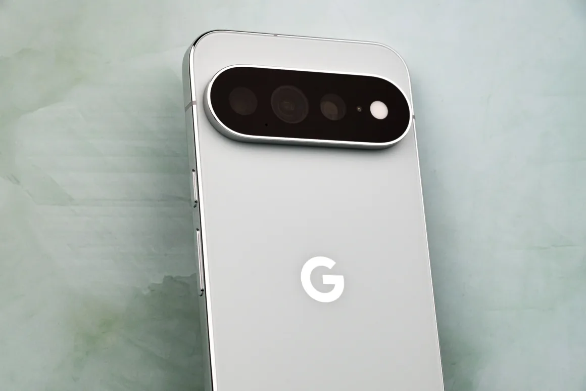 Google Pixel 11 Pro XL İncelemesi: Küçük Ama Anlamlı Bir Adım 19 Açık gri bir akıllı telefonun arka yüzünü yakın ve açılı biçimde gösteren görüntü; üst bölümde üç lens ve flaş içeren belirgin, yatay ve kapsül biçimli bir kamera modülü, gövdenin ortasında ise beyaz bir "G" logosu bulunuyor.