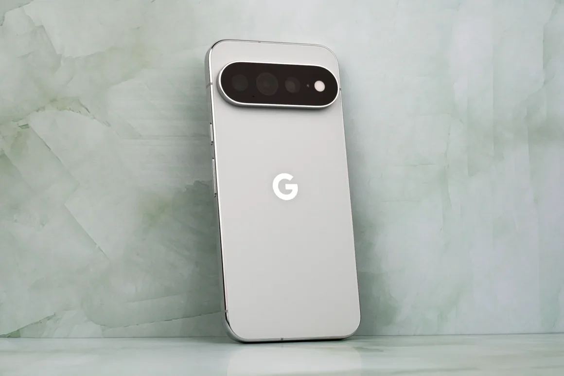Google Pixel 11 Pro XL İncelemesi: Küçük Ama Anlamlı Bir Adım 23 Arka tarafında belirgin yatay bir kamera çubuğu bulunan gümüş renkli akıllı telefon, açık yeşil mermer bir arka plan önünde dik duruyor.