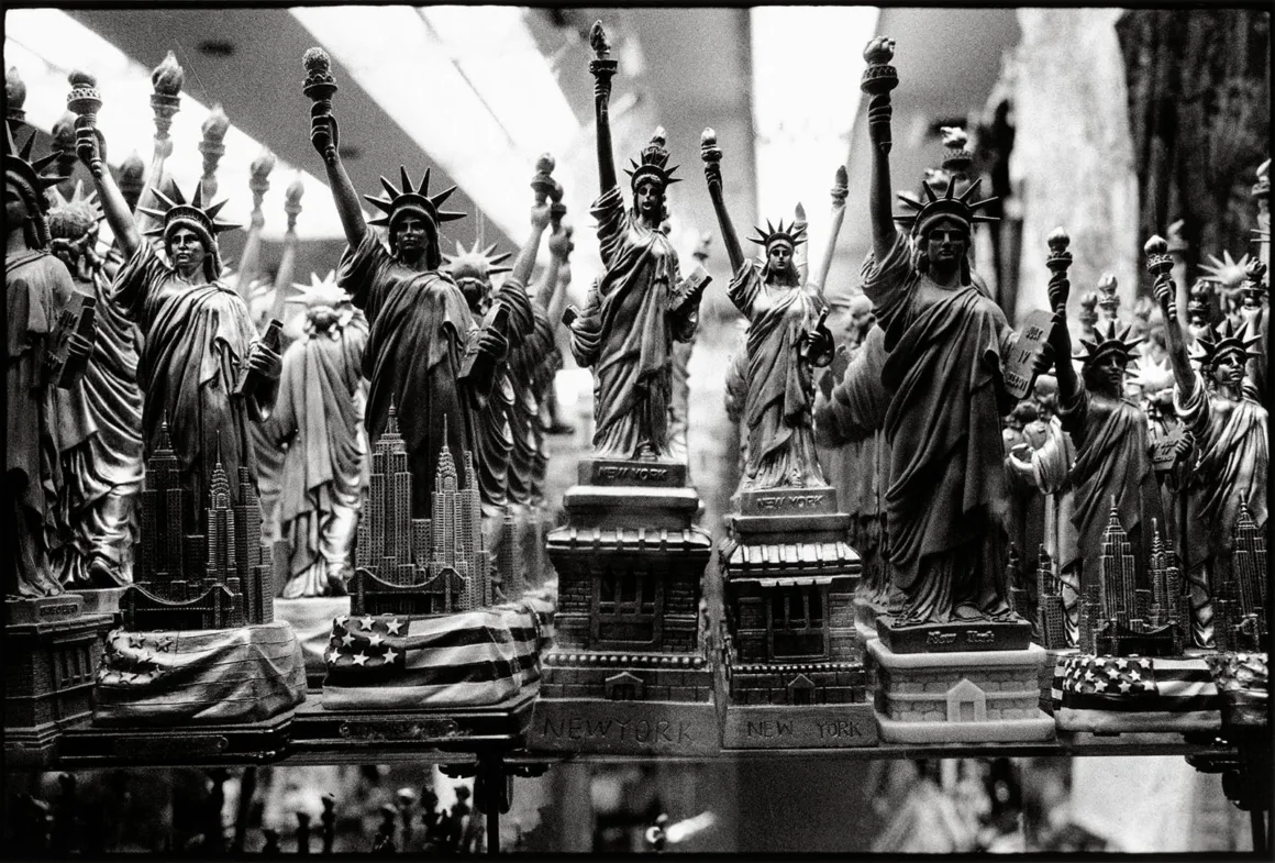 Bir rafta sergilenen, çoğunda minyatür New York silüeti bulunan Özgürlük Heykeli hediyelikleri.