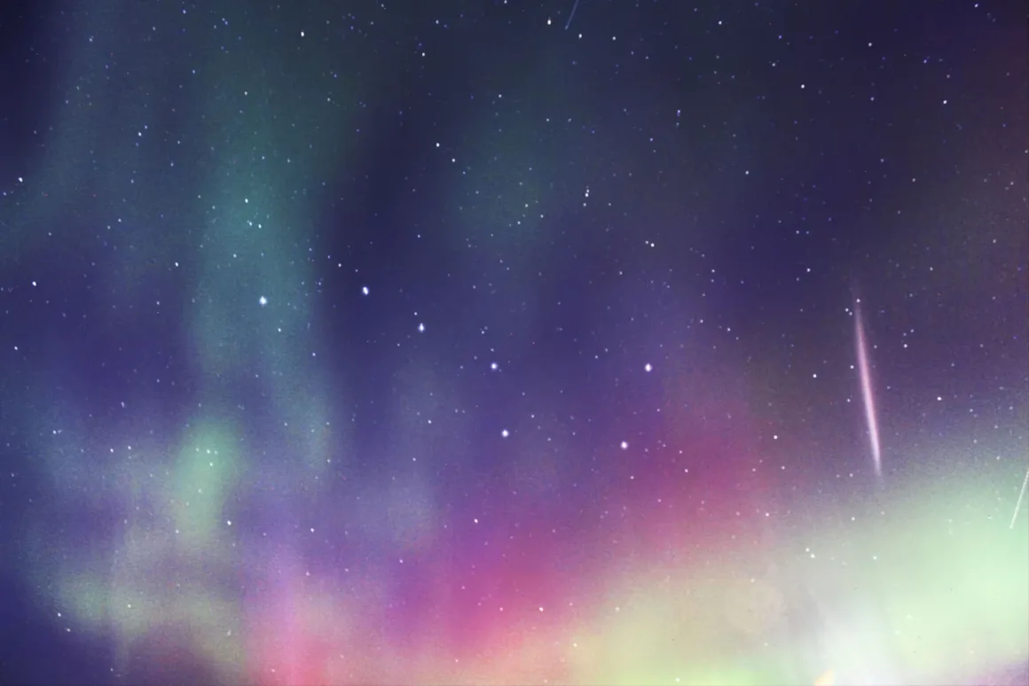 Dünyanın En Karanlık Gökyüzlerinin Güzelliğini Yansıtan 31 Ödüllü Fotoğraf 34 A vibrant aurora borealis displays green and magenta light across a dark, star-filled night sky.