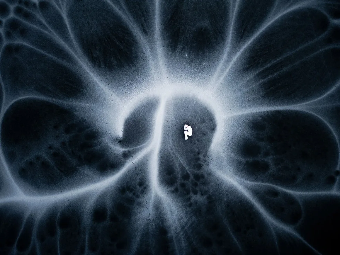 Minimalist Fotoğraf Ödülleri 2026: Kazananlar Sadeliğin Gücünü Gösteriyor 26 A small, white, fetal-shaped figure lies in the center of a dark, swirling, abstract pattern resembling a nebula or fluid.