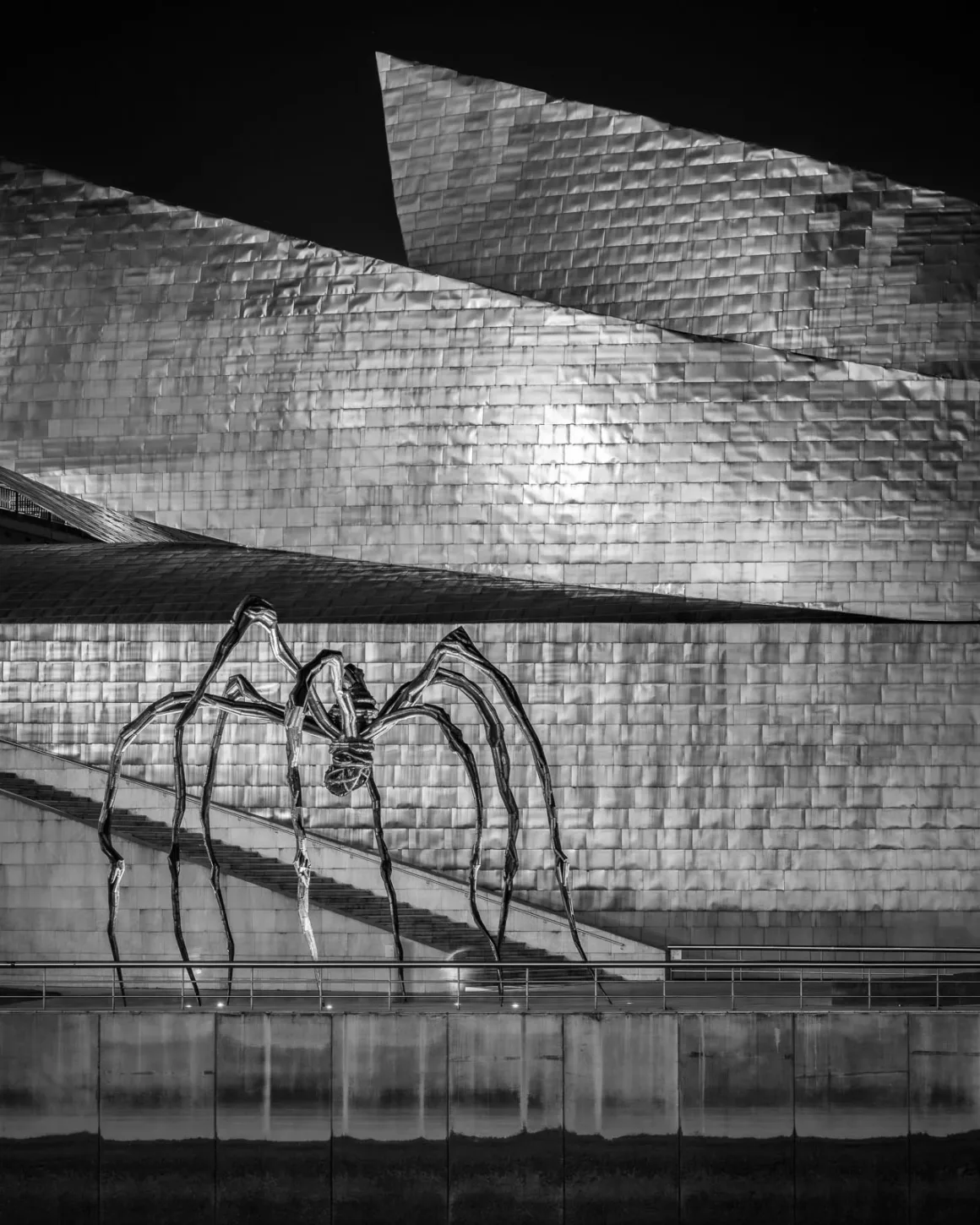 Minimalist Fotoğraf Ödülleri 2026: Kazananlar Sadeliğin Gücünü Gösteriyor 30 A large metal spider sculpture stands on a concrete terrace in front of a building with angular, tiled metallic walls.
