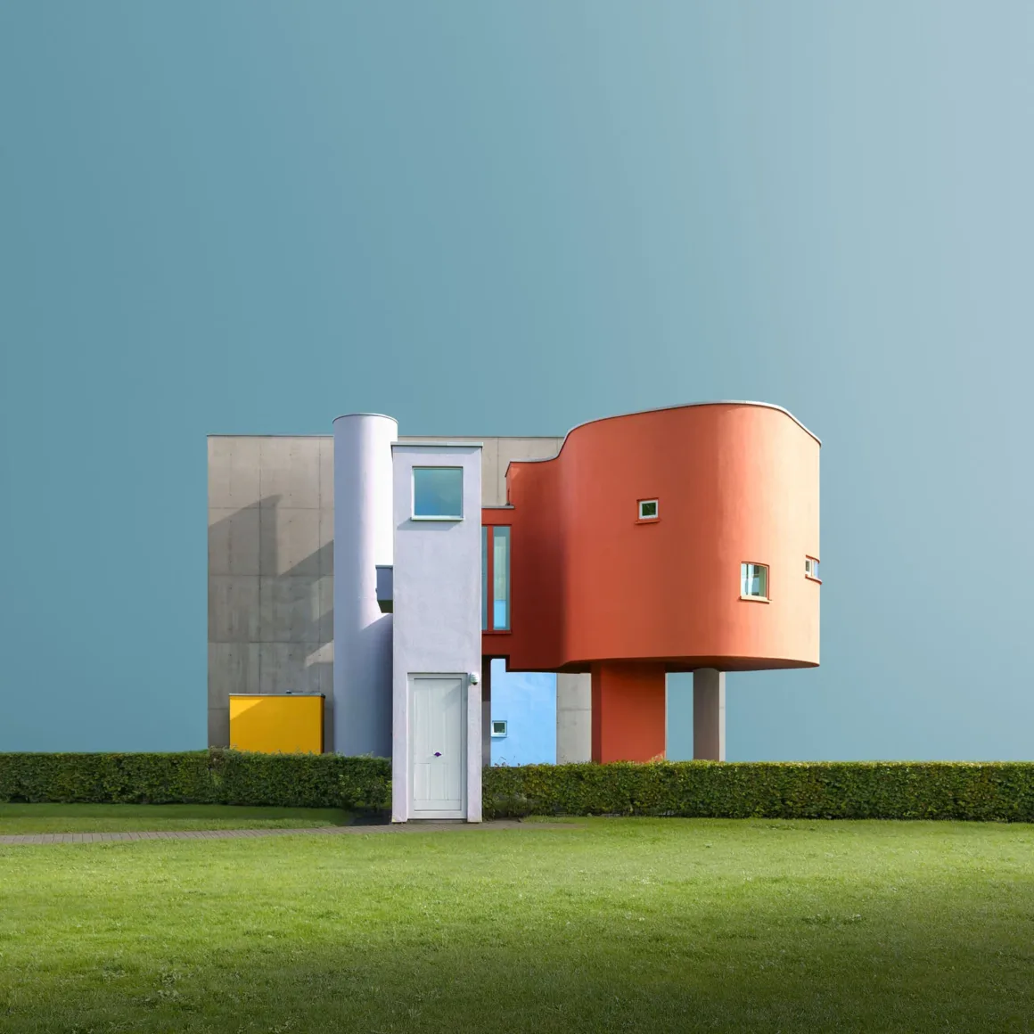 Minimalist Fotoğraf Ödülleri 2026: Kazananlar Sadeliğin Gücünü Gösteriyor 28 A modern, colorful building with geometric shapes and a cantilevered orange section stands behind a manicured hedge and lawn.