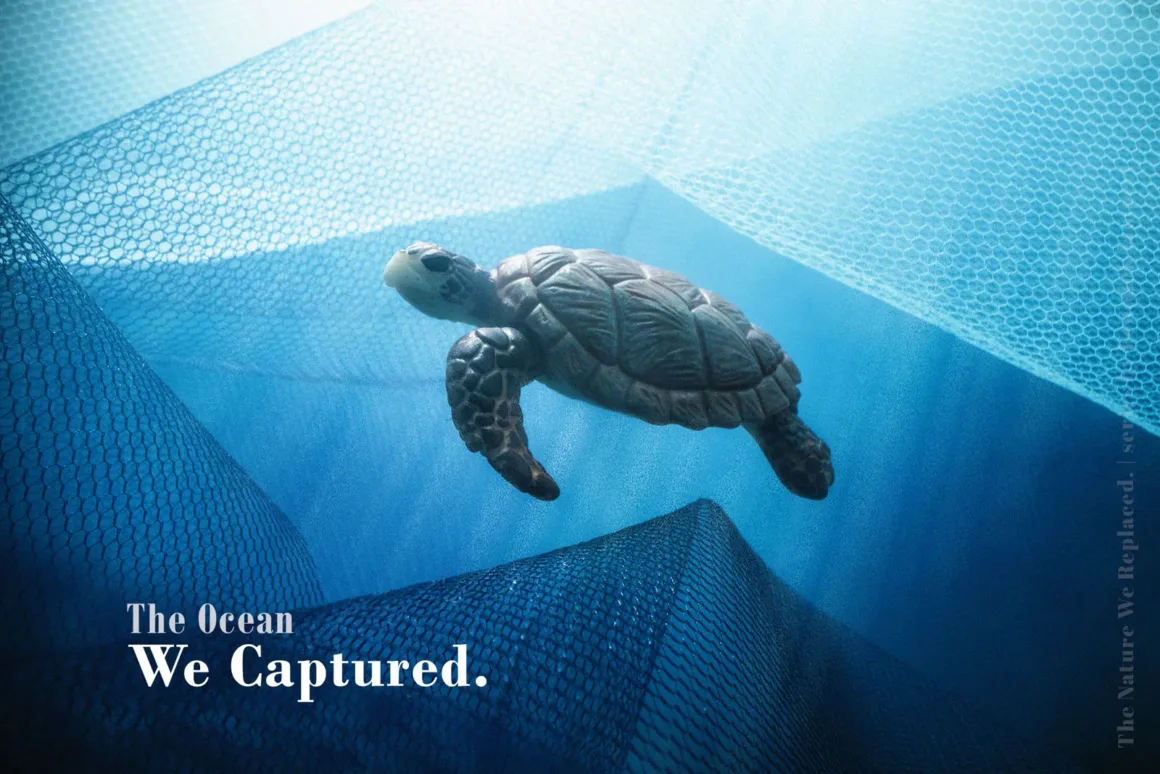 Doğanın Yerini Atıkların Aldığı Bir Dünya: Benedek Lampert'in Yeni Fotoğraf Serisi 3 Mavi balık ağlarının arasında yüzen bir deniz kaplumbağası. Sol altta 'The Ocean We Captured' yazısı bulunuyor.