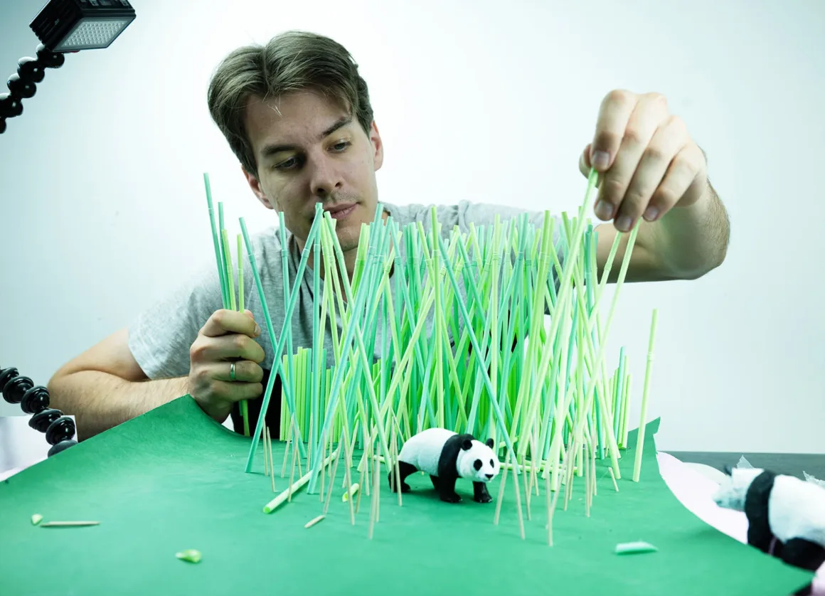 Doğanın Yerini Atıkların Aldığı Bir Dünya: Benedek Lampert'in Yeni Fotoğraf Serisi 8 A man carefully places green plastic straws into a green base to create a forest scene for a small panda figurine.