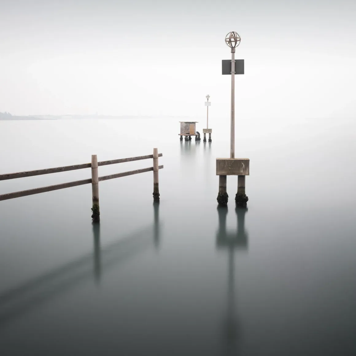 Minimalist Fotoğraf Ödülleri 2026: Kazananlar Sadeliğin Gücünü Gösteriyor 35 A wooden fence and several navigation markers stand in calm, misty water under a pale sky.