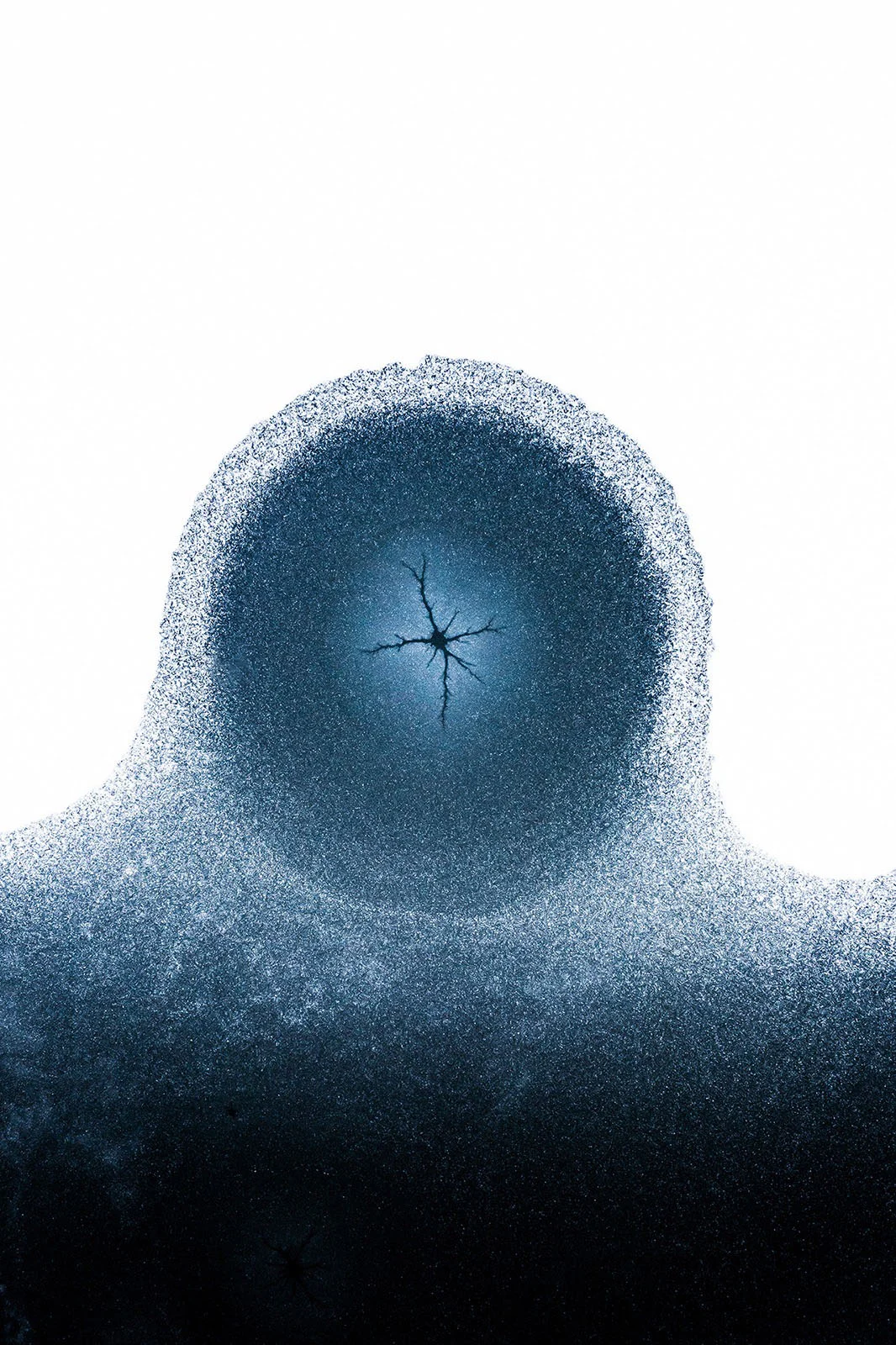 Minimalist Fotoğraf Ödülleri 2026: Kazananlar Sadeliğin Gücünü Gösteriyor 20 Beyaz kar örtüsünün ortasında, yıldız biçimli bir yarık barındıran koyu renkli dairesel buz deseni.