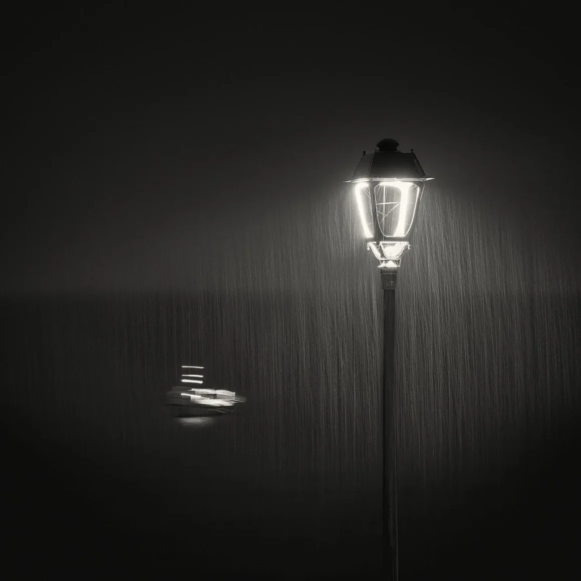 Minimalist Fotoğraf Ödülleri 2026: Kazananlar Sadeliğin Gücünü Gösteriyor 44 A black and white image of a glowing street lamp in heavy rain, with a blurred, illuminated boat visible in the distance.