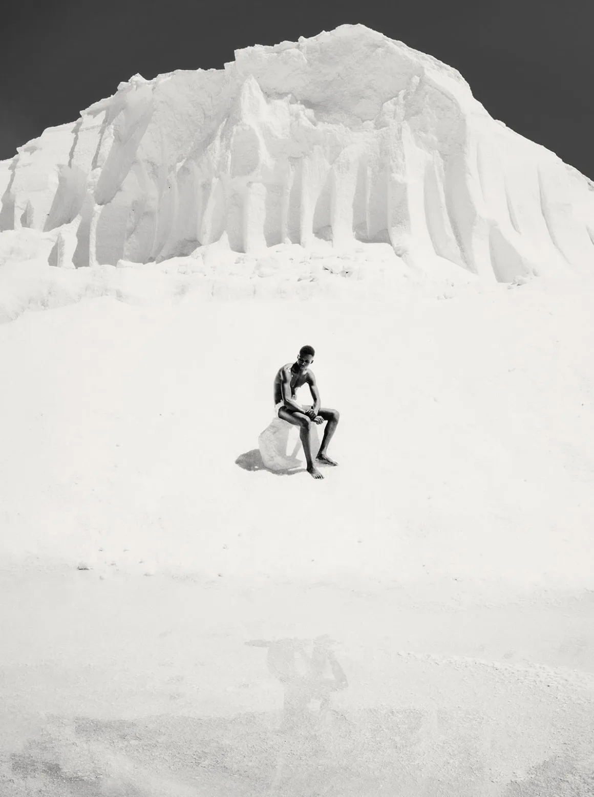 Minimalist Fotoğraf Ödülleri 2026: Kazananlar Sadeliğin Gücünü Gösteriyor 54 A shirtless person sits on a small rock in the middle of a vast, white salt flat with a large, textured salt mound behind them.