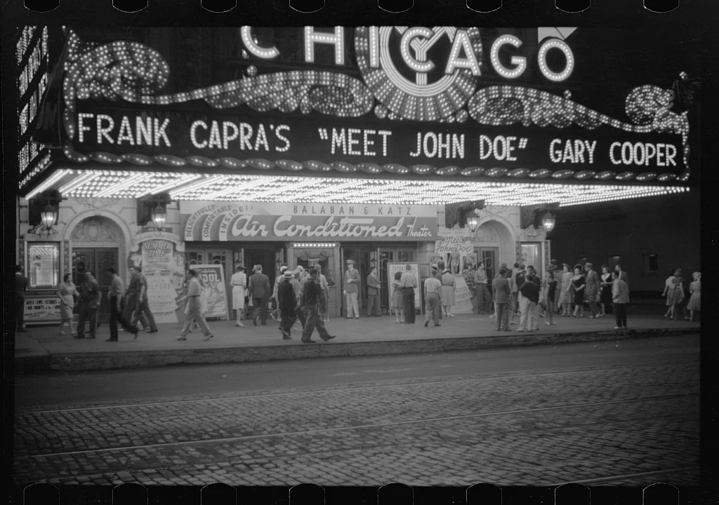Klimalı Sinemalar Yaz Gişe Filmlerini Nasıl Doğurdu? 16 İnsanlar, Gary Cooper’ın başrolünde yer aldığı Meet John Doe filminin afişini sergileyen Chicago Theatre’ın önündeki kaldırımda yürüyor.