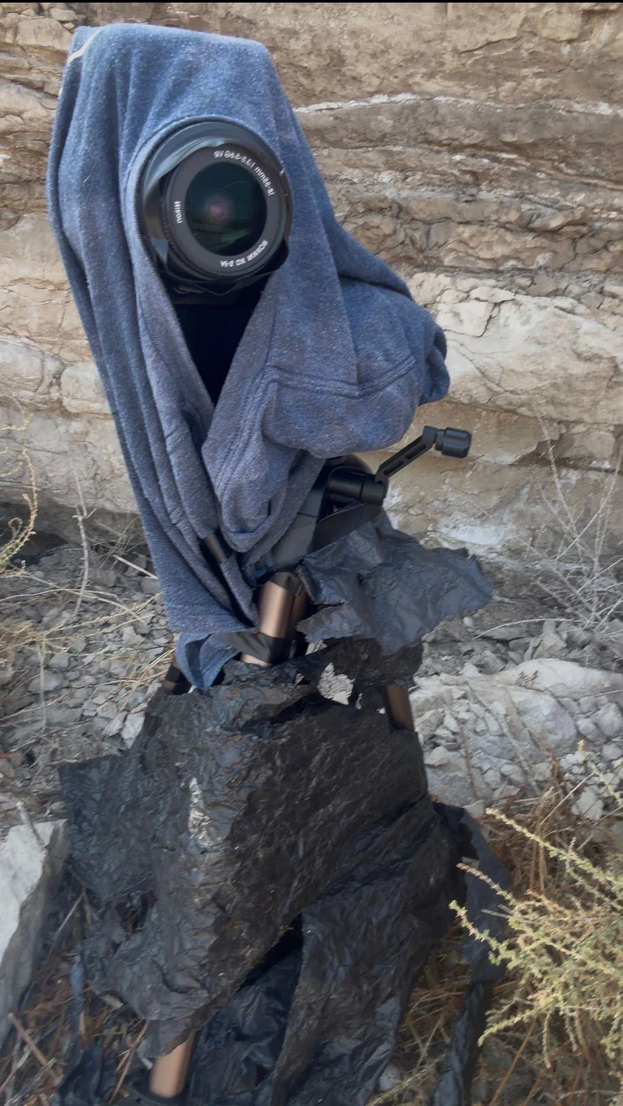 İki Fotoğrafçı Kusursuz Tutulma Karesi İçin Bir Yıl Hazırlandı, Her Şey 30 Saniyeye Kaldı 29 Tripod üzerindeki bir fotoğraf makinesi mavi bir tişörtle örtülmüş ve kısmen siyah plastikle sarılmış halde kayalık bir yamacın önüne yerleştirilmiş.