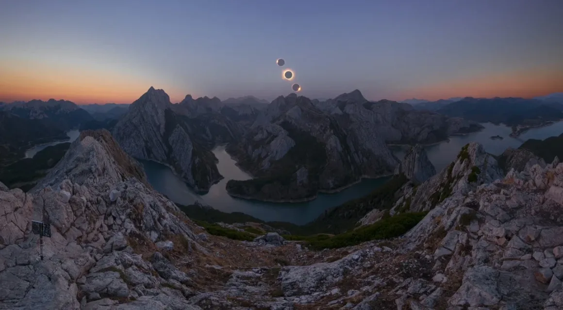 Angel Fux, Tam Güneş Tutulmasını Tek Bir Fotoğrafta Zamana Dönüştürdü 20 A panoramic view of jagged, rocky mountains surrounding a winding river at twilight, with three solar eclipses in the sky.