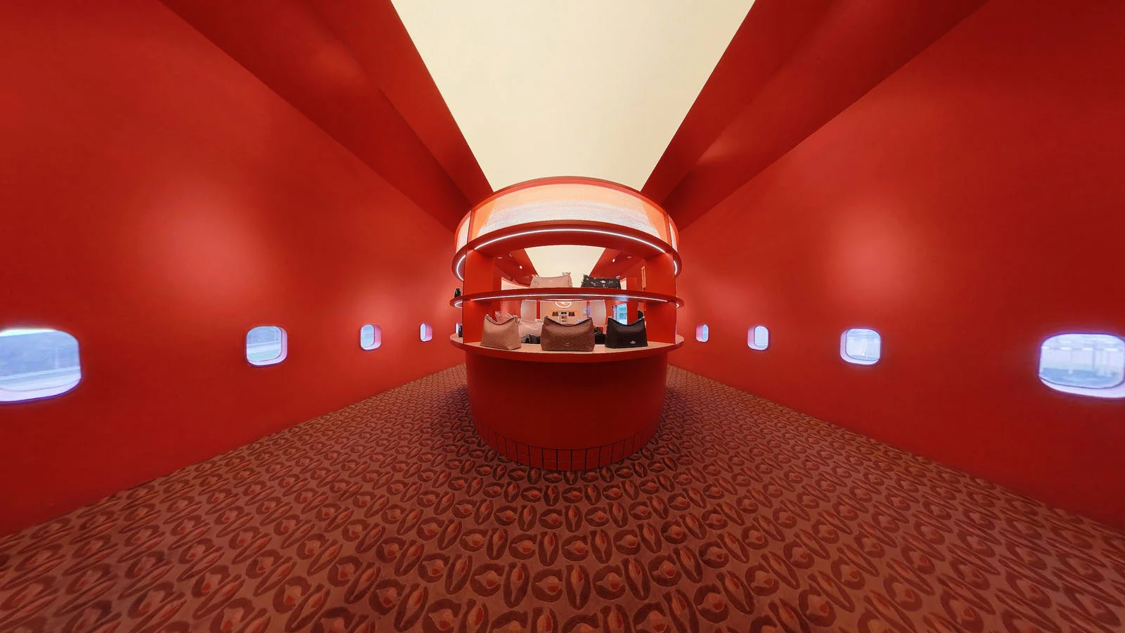 Sony World Photography Awards 2027’ye Katılmanız İçin 15 İlham Verici Fotoğraf 23 A symmetrical, red-walled room with a circular display shelf in the center holding handbags, featuring small windows along the sides and a patterned carpet.