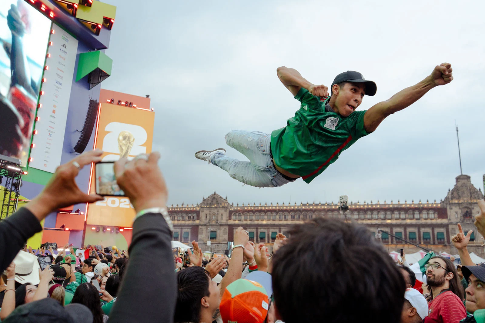 Sony World Photography Awards 2027’ye Katılmanız İçin 15 İlham Verici Fotoğraf 22 A man in a green soccer jersey is held horizontally in the air by a crowd of people in front of a large digital screen.