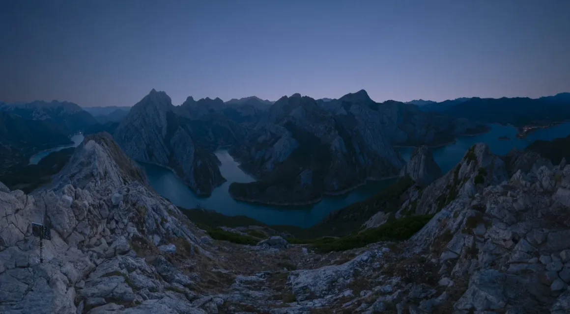 Angel Fux, Tam Güneş Tutulmasını Tek Bir Fotoğrafta Zamana Dönüştürdü 23 A panoramic view of a winding river flowing through a deep valley surrounded by jagged, rocky mountain peaks at twilight.